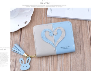 Close-up of color-block zip wallet with stitched hearts, tassel and bunny charm