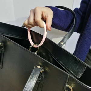 Pink silicone ring keychain with golden clasp attached to a black leather handbag
