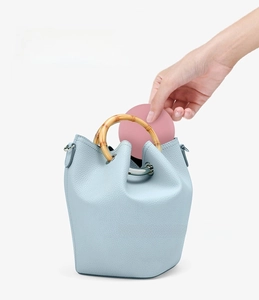 Pink portable LED compact makeup mirror being placed inside a blue lychee leather handbag