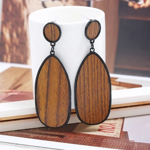 Détail de boucles d'oreilles pendantes en bois avec cadre noir et texture de grain naturel