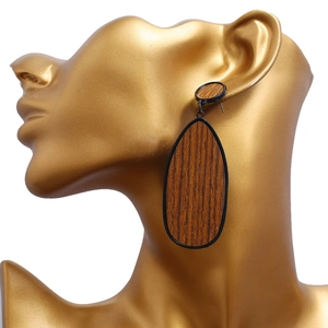 Gros plan d'une boucle d'oreille en bois en forme de larme avec bordure en métal noir