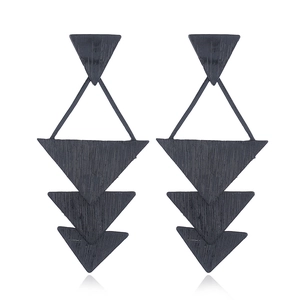 Détail de boucles d'oreilles triangulaires superposées noires avec texture de bois