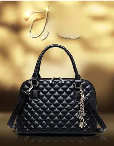 Detail of black quilted handbag with gold-tone butterfly charm and elegant metal hardware