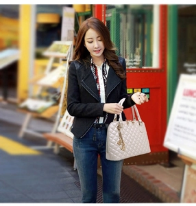 Fashionable beige quilted handbag with lattice embroidery pattern held by stylish model