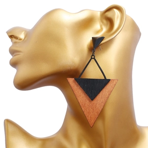 Détail de boucles d'oreilles triangulaires en bois et métal noir portées par un mannequin