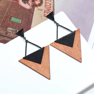 Détail de boucles d'oreilles géométriques en bois brun et métal noir sur fond blanc