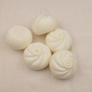 Five slow-rebound white steamed buns toys with yellow dots on beige textured fabric