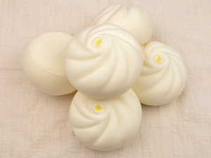 Detail shot of five squishy PU steamed buns with spiral textures on beige fabric