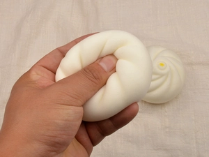 Macro detail of hand squeezing a soft, slow rebound bun squishy toy for stress relief