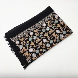 Close-up of black cashmere-like shawl featuring intricate floral embroidery and fringe