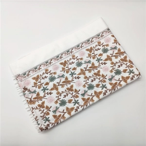 Close-up of white cashmere-like scarf featuring intricate brown and green floral embroidery