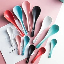 Flat lay macro of colorful ceramic spoons in various sizes on a pink and white background