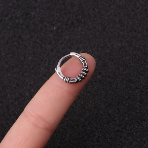Vintage silver nose ring with twisted texture and small beads displayed on a fingertip