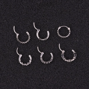 Vintage silver stainless steel nose rings and twisted hoop earrings set on dark background