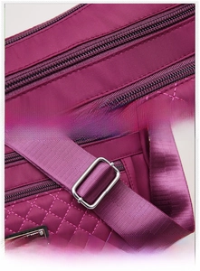 Detail of purple nylon crossbody bag featuring quilted stitching and adjustable strap buckle