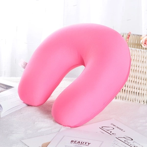 Detailed view of a soft pink U-shaped neck pillow with foam filling on white plush surface