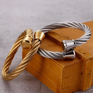 Cable style stainless steel open bangles in gold and silver finish on a vintage wooden box