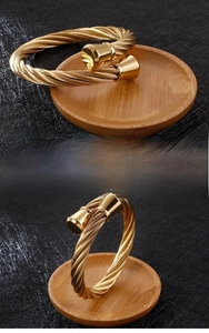 Macro detail of golden fine steel twisted rope open bangle with smooth trumpet ends