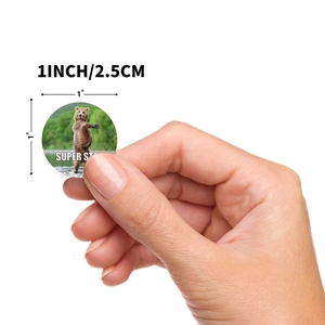 Handheld view of 1-inch round brown bear stickers for kids toys and gift decoration