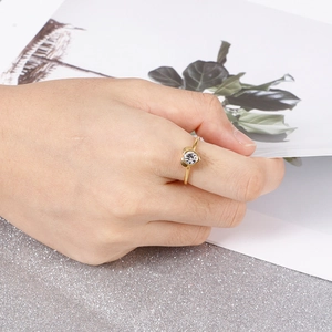 Elegant gold heart ring with round zircon stone shown on hand with floral card background