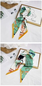 Close-up of long narrow silk scarf with green horse chain prints on woven bag