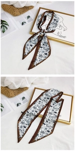Detailed pattern of a long silk scarf with giraffe prints next to a sun hat