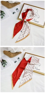 Detailed flat lay of red and cream twilly scarf with horse pattern and gold edging