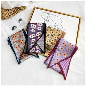 Close-up of four floral silk scarves with elegant patterns on a white textured backdrop