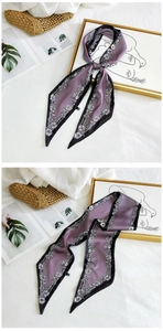 Detailed view of a purple long silk scarf with black floral patterns and accessories