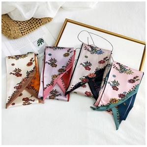 Silk neck scarves with floral prints displayed on a white background with decorative bag