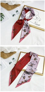 Detailed view of patterned silk scarf with floral prints styled on a white bed linen
