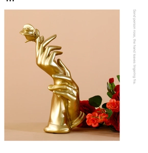 Detail of golden resin hand sculpture holding a rose for luxury home decor