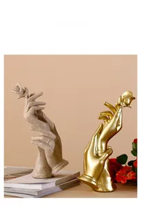 Detail of artistic hand sculptures holding a rose in sandstone and golden finish