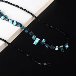 Handmade beaded sunglasses chain with shell accents on modern black and white background