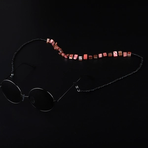 Handmade beaded shell sunglasses chain with vintage round black frames on dark background