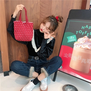 Primo piano di una mini borsa tote in tela rossa con pois bianchi su una modella