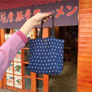Dettaglio della trama della borsa a pieghe blu scuro a pois con manico nero e chiusura