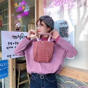 Dettaglio di una borsa tote in velluto a coste rosa a pois bianchi portata da una modella