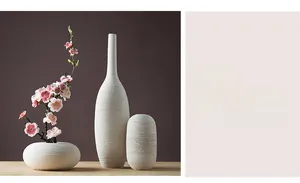 Makro-Detail von weißen Keramikvasen im Set mit horizontaler Textur auf Holztisch