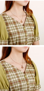 Detail of rose gold necklace with a sparkling round diamond pendant on a model wearing plaid
