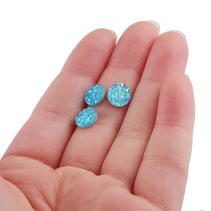Macro shot of 8mm blue round resin faux druzy crystals held in palm for size reference