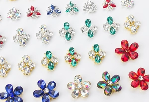 Macro view of crystal flower nail art charms with colorful rhinestones in gold and silver settings