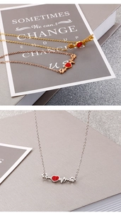 Détail macro du collier patte et cœur en or et argent avec zircon rouge
