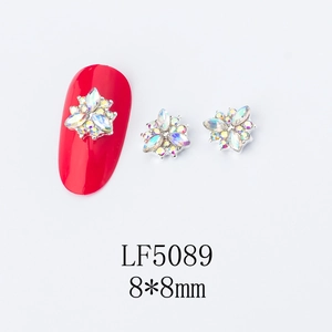 Detailed view of 8x8mm gold flower nail art charm with AB rhinestones on red nail