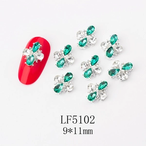 Detailed view of 9x11mm green and clear flower nail art charms on red nails
