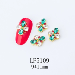 Detail view of 9x11mm flower nail art charm with emerald rhinestones on red nail