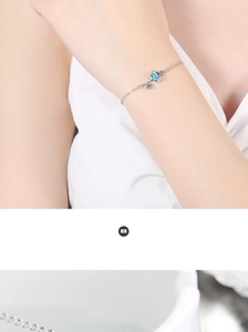Detailed close-up of a silver planet and key charm bracelet worn on a woman's wrist