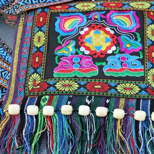 Detailed close-up of vibrant floral embroidery with colorful tassels and wooden beads