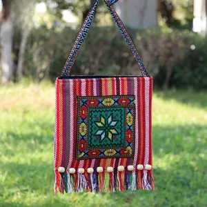 Detailed shot of ethnic crossbody bag featuring floral embroidery and colorful tassels