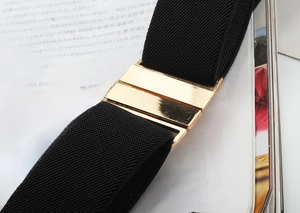 Detail of black elastic belt with polished gold rectangular metal buckle on a magazine